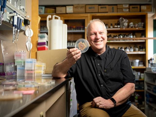 Michael Freitag in a lab, holding a clear round container with a specimen 